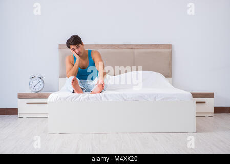 Jeune homme Waking up in bed Banque D'Images