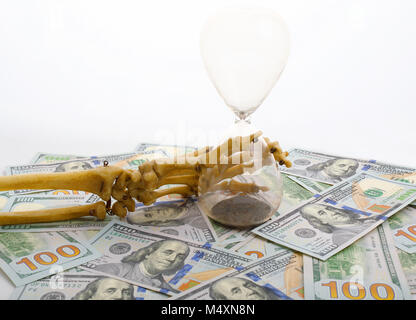 Les doigts de squelette holding sand-verre placé sur dollars. concept de temps - de l'argent et la mort. Banque D'Images