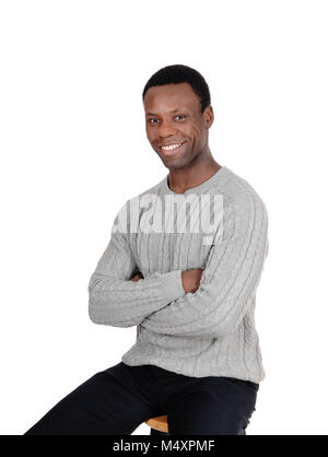 Un heureux et beau African American man assis les bras croisés dans un gris plus doux, isolée pour fond blanc Banque D'Images