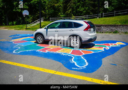 Voiture blanche garée sur une carte colorée des États-Unis peint sur l'asphalte. Banque D'Images