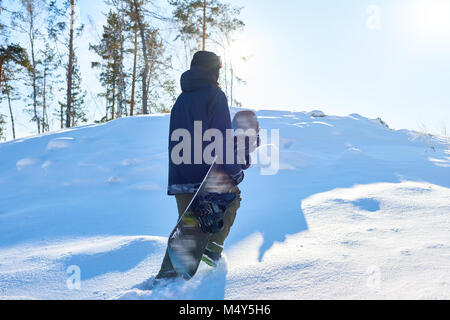 Portrait de jeune planchiste exécutant up snowy hill pour aller équitation freestyle sur sentier dans les bois sauvages, copy space Banque D'Images