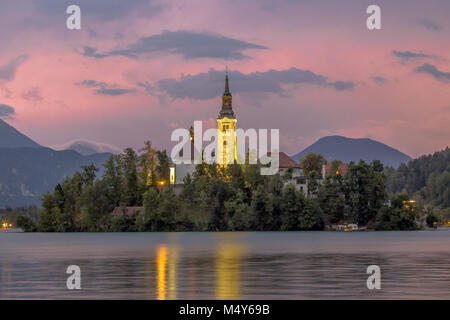 Scène paysage Lac de Bled avec l'église St Mary sur l'île et les montagnes en toile de fond sous ciel d'orage rose, Slovénie, Europe Banque D'Images