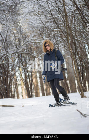 Femme avec appareil photo numérique en marche bois après les chutes de neige fraîche Banque D'Images