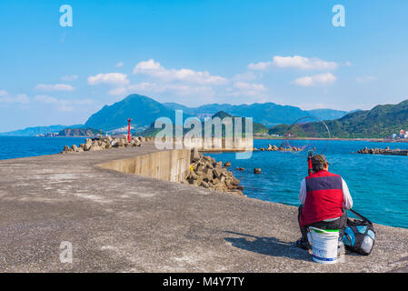 KEELUNG, TAÏWAN - 04 avril : pêcheur local assis sur une barrière de la capture du poisson dans des vagues côtières Badouzi park sur Avril 04, 2017 à Keelung Banque D'Images