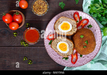 Grandes escalopes juteuses farci d'oeuf dur sur un fond de bois sombre. Scottish escalope. La vue de dessus Banque D'Images