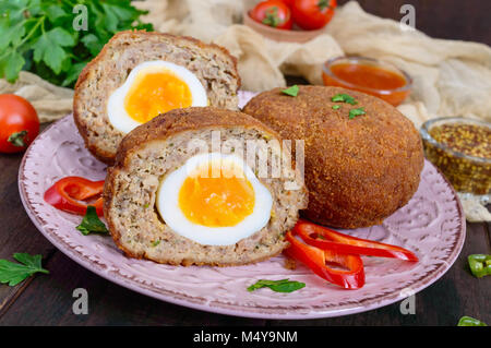 Grandes escalopes juteuses farci d'oeuf dur sur un fond de bois sombre. Scottish escalope. Banque D'Images