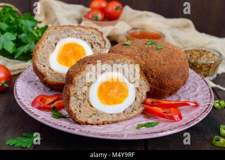 Grandes escalopes juteuses farci d'oeuf dur sur un fond de bois sombre. Scottish escalope. Banque D'Images