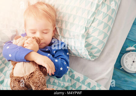 Trois ans enfant de dormir dans le lit avec réveil Banque D'Images