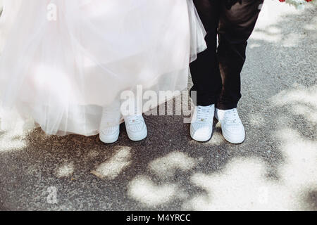Les jambes de la mariée sur la chaussée dans des chaussures et des robes Banque D'Images