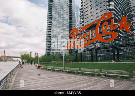 Les gens sur la promenade Boardwalk près du bras en signe emblématique Plaza State Park avec vue sur Ed Koch Queensborough Bridge à distance, Long Island City, New York City, USA Banque D'Images