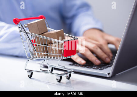 Man with Miniature de boîtes de carton dans le panier sur le bureau Banque D'Images