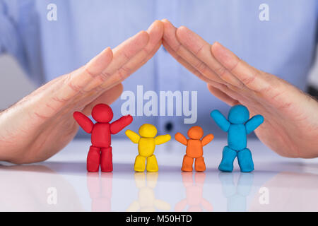 La main de l'homme Protéger la famille colorée composée d'argile sur blanc 24 Banque D'Images