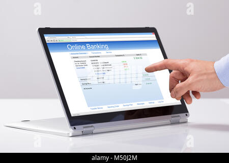 Close-up de la main des hommes utilisant les services bancaires en ligne sur ordinateur portable hybride sur le blanc 24 Banque D'Images