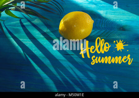 Hello summer concept avec citron juteux et la feuille de palmier en plein soleil sur fond bleu contraste Banque D'Images