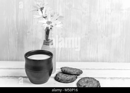Les marguerites et les cookies et le lait sur le tableau noir et blanc Banque D'Images