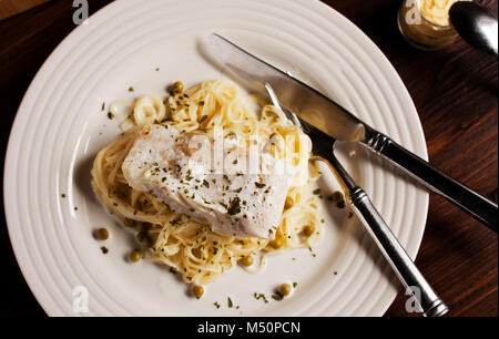 Un coup vertical de poisson blanc poché et pois sur lit de spaghetti Banque D'Images