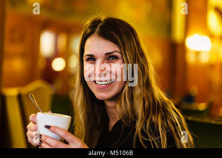 Close-up of woman's hands holding cell phone alors que boire du café et manger des cookies avoine dans le café moderne Banque D'Images