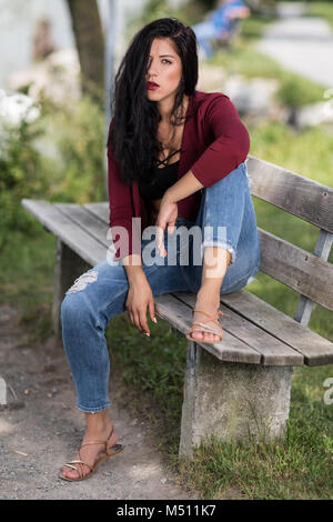 Jeune femme assise sur un banc en bois Banque D'Images