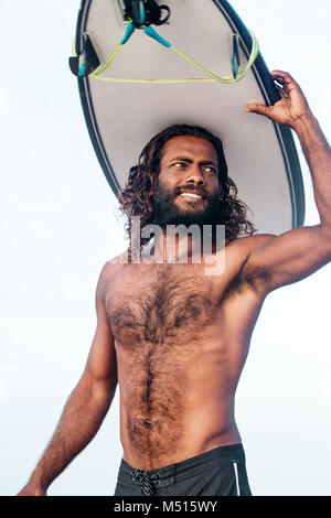 Surfer avec une planche de surf sur sa tête Banque D'Images