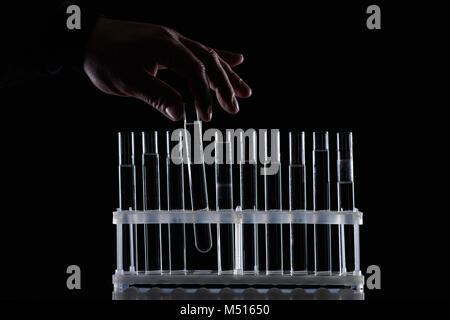 Portrait of female chemist en tenant le tube de verre de stand isolated on black Banque D'Images