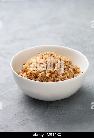 Alimentation nourriture. le quinoa cuit dans un bol blanc sur un fond noir en gris Banque D'Images