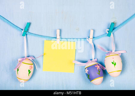 Œufs de Pâques et sur une corde sur un fond en bois bleu. La vie encore Pâques peut être utilisé comme une carte postale. Banque D'Images