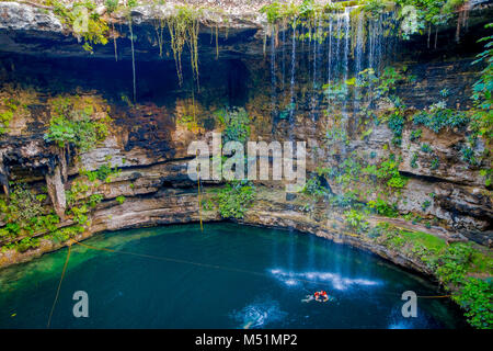 CHICHEN ITZA, MEXIQUE - 12 NOVEMBRE 2017 : balades Couple non identifié en bas et à l'étage alors qu'une femme blonde pose pour la caméra dans le magnifique Cenote Ik-Kil étang avec de nombreuses personnes natation, près de Chichen Itza au Mexique Banque D'Images