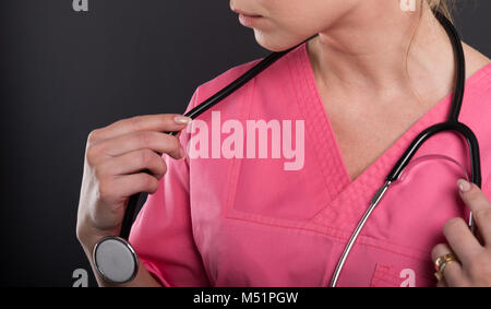 Close-up of beautiful young doctor putting sur son stéthoscope sur fond noir Banque D'Images