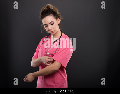 Magnifique Portrait de jeune médecin organiser son manchon sur fond noir avec copyspace zone publicitaire Banque D'Images