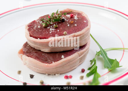 Les Tournedos : un petit tour d'épaisseur coupé d'un filet de boeuf dans une assiette blanche background Banque D'Images