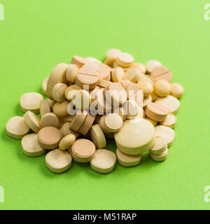 Tas de capsules beige vert sur table. Tas de pilules. Banque D'Images