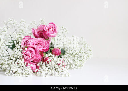 Style de mariage stock photo. Nature morte avec roses et gypsophile Gypsophila fleurs sur fond de table blanc. Composition florale. Image pour blog ou les médias sociaux. Banque D'Images