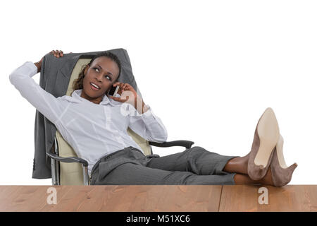 Femme d'affaires africaine assise à son bureau et de parler par téléphone isolé sur fond blanc Banque D'Images