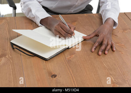 Femme d'affaires africaine assise à son bureau et de planification isolé sur fond blanc Banque D'Images