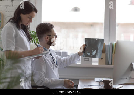 Doctors discussing intestins xray at medical office Banque D'Images