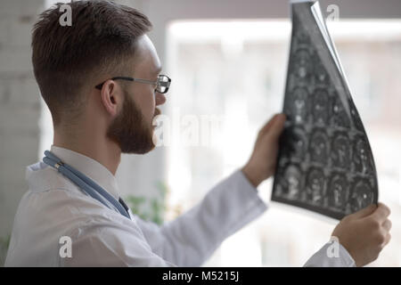 Closeup portrait of man intellectuelle avec le personnel des soins de santé, à la recherche de blanche labcoat cerveau x-ray image radiographie, tomodensitométrie, IRM, clinique office b Banque D'Images