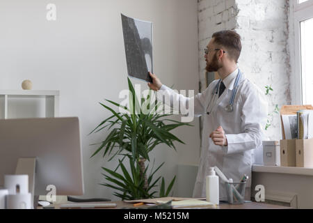 Closeup portrait of man intellectuelle avec le personnel des soins de santé, à la recherche de blanche labcoat cerveau x-ray image radiographie, tomodensitométrie, IRM, clinique office b Banque D'Images