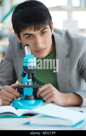 En étudiant les hommes de laboratoire tout en travaillant avec microscope et prendre des notes Banque D'Images