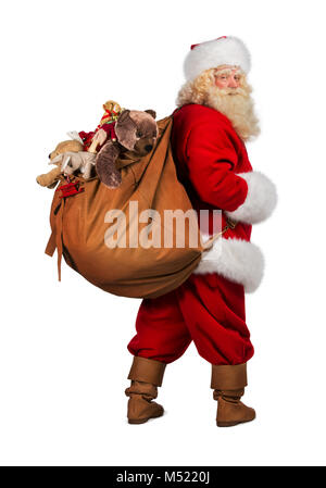 Portrait du vrai Père Noël exerçant son gros sac plein de cadeaux de derrière, isolé sur fond blanc Banque D'Images