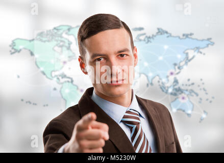 Portrait of young man standing in front of grande carte du monde et à la recherche à l'appareil photo. Les emplacements de serveur et les connexions en ligne sont affichées sur virtua Banque D'Images