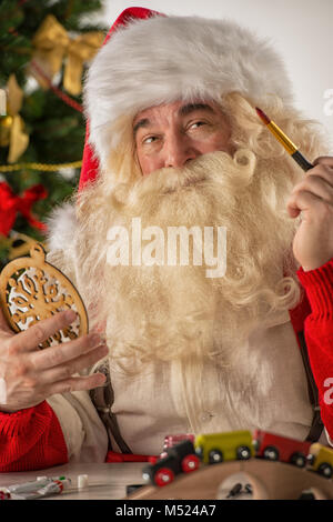 Le Père Noël dans son atelier faire de nouveaux jouets pour des cadeaux de Noël pour les enfants dans le monde Banque D'Images