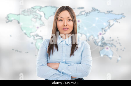 Portrait of young woman standing in front of grande carte du monde et à la recherche à l'appareil photo. Les emplacements de serveur et les connexions en ligne sont affichées sur virt Banque D'Images