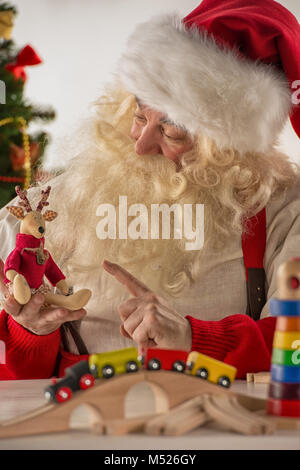 Le Père Noël dans son atelier faire de nouveaux jouets pour des cadeaux de Noël pour les enfants dans le monde Banque D'Images