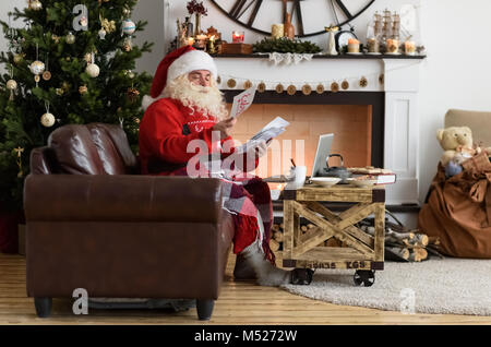 Santa Claus travaux près de l'arbre de Noël à la maison. Lecture des lettres de childrens Banque D'Images