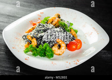 Pâtes noires aux crevettes et fruits de mer sur un fond de bois noir Banque D'Images