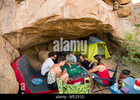 Groupe d'amis camping et de cartes à jouer en vertu de Spitzkoppe rochers, région d'Erongo, Namibie Banque D'Images