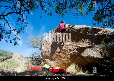 Tapis d'exercice ci-dessous young woman climbing boulder, Brandberg, Damaraland, Namibie Banque D'Images