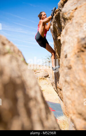 Vue latérale du jeune femme escalade rocher, le Brandberg, Damaraland, Namibie Banque D'Images