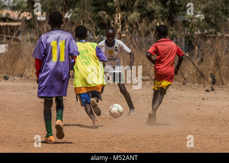 Les jeunes footballeurs ghanéens sont vus jouer pendant un match de football au Football Club TimTooni, juste à l'extérieur de Tamale dans le Nord du Ghana. De même que les entraîneurs de football de Londres, le temps était passé avec les enfants ici en leur enseignant de nouvelles compétences et se terminant par un grand match de football. Ces régions du Ghana sont si éloignées et les niveaux de pauvreté sont parmi les plus bas au monde. Banque D'Images