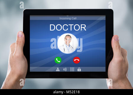 Close-up of a person's Hand Holding Tablet avec le médecin sur l'affichage des appels entrants Banque D'Images